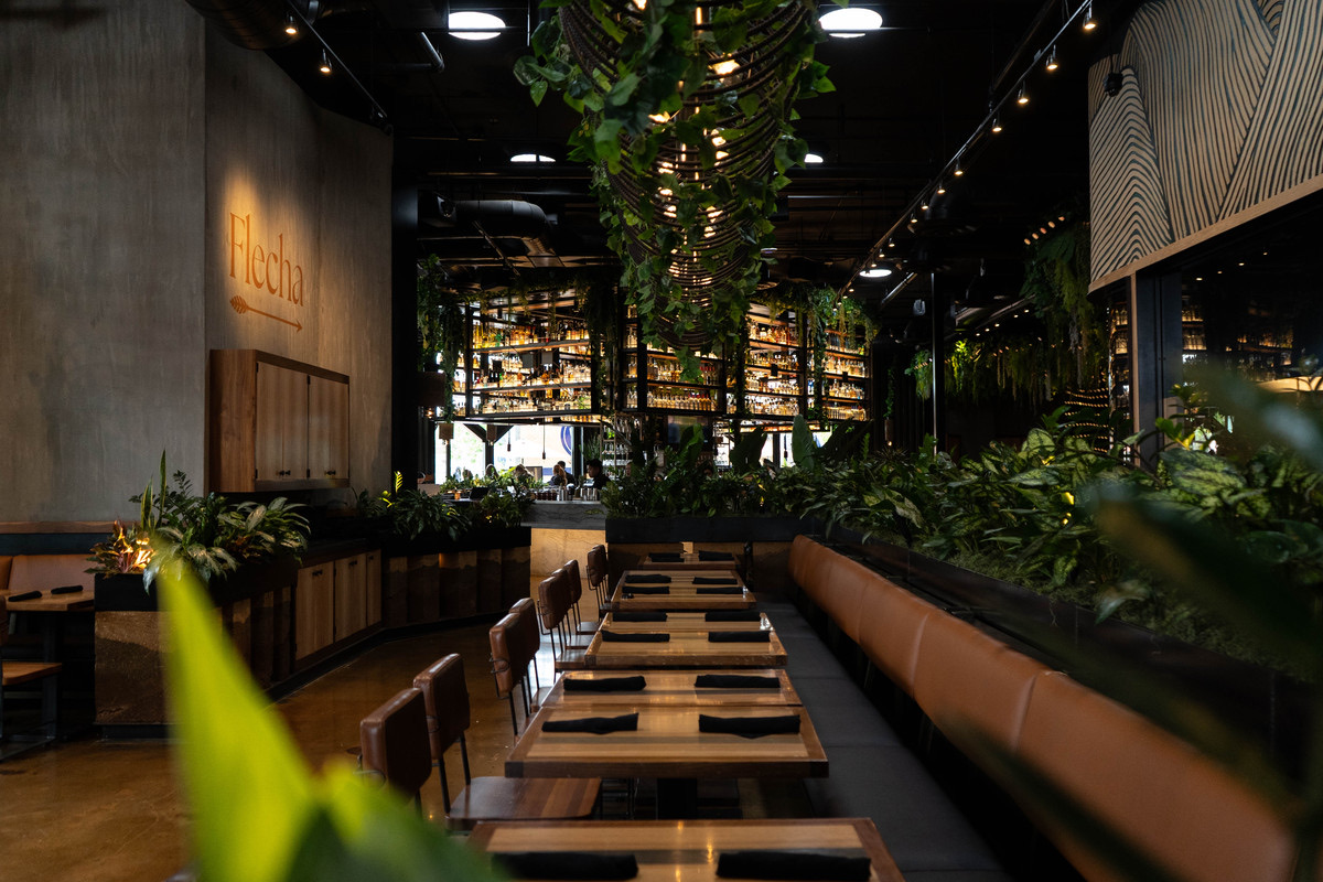 Flecha Cantina’s dining room, with greenery draped over a long banquette